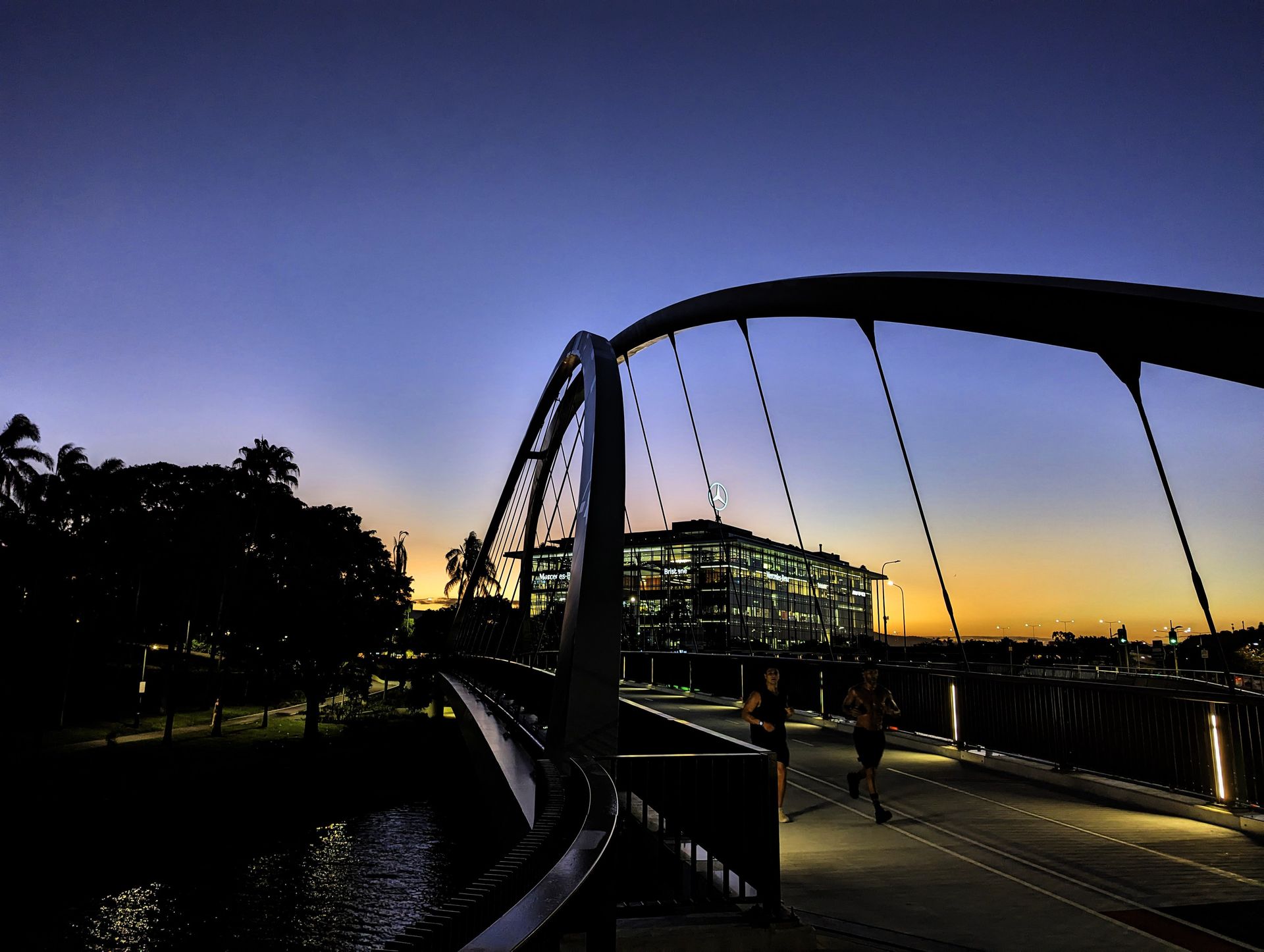 Joggers cross the bridge at sunset
