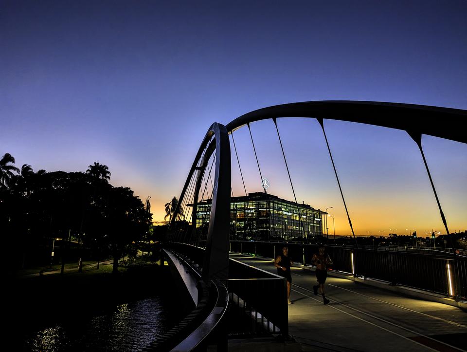 Joggers cross the bridge at sunset