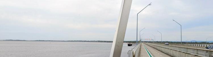 A featureless concrete bridge spanning over a vast bay, a green painted bike lane disappearing into the distance